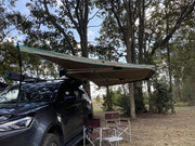 Vehicle with a 30 Second 180 Degree Wing Awning extended over camping chairs for outdoor shade