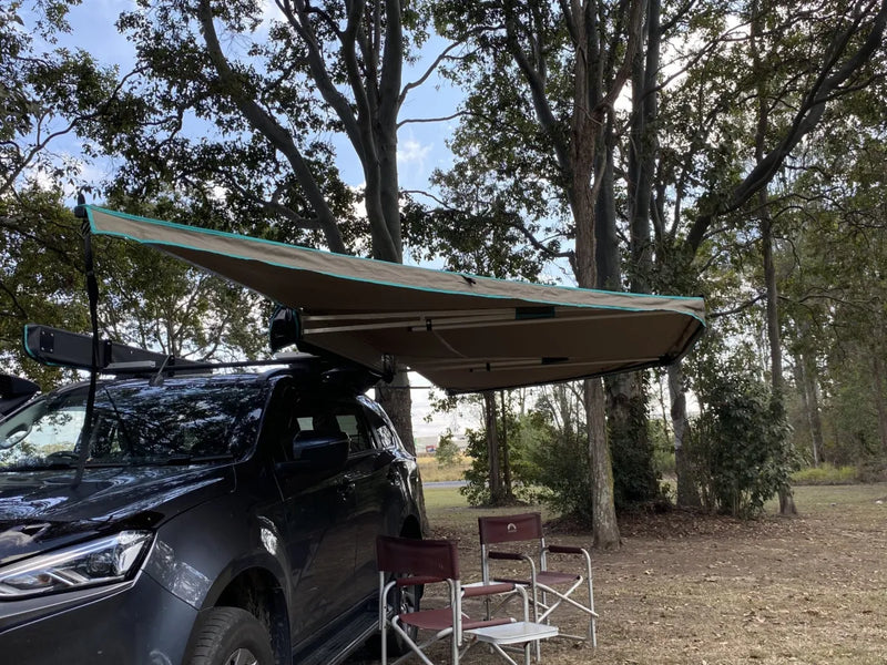 Vehicle with a 30 Second 180 Degree Wing Awning extended over camping chairs for outdoor shade