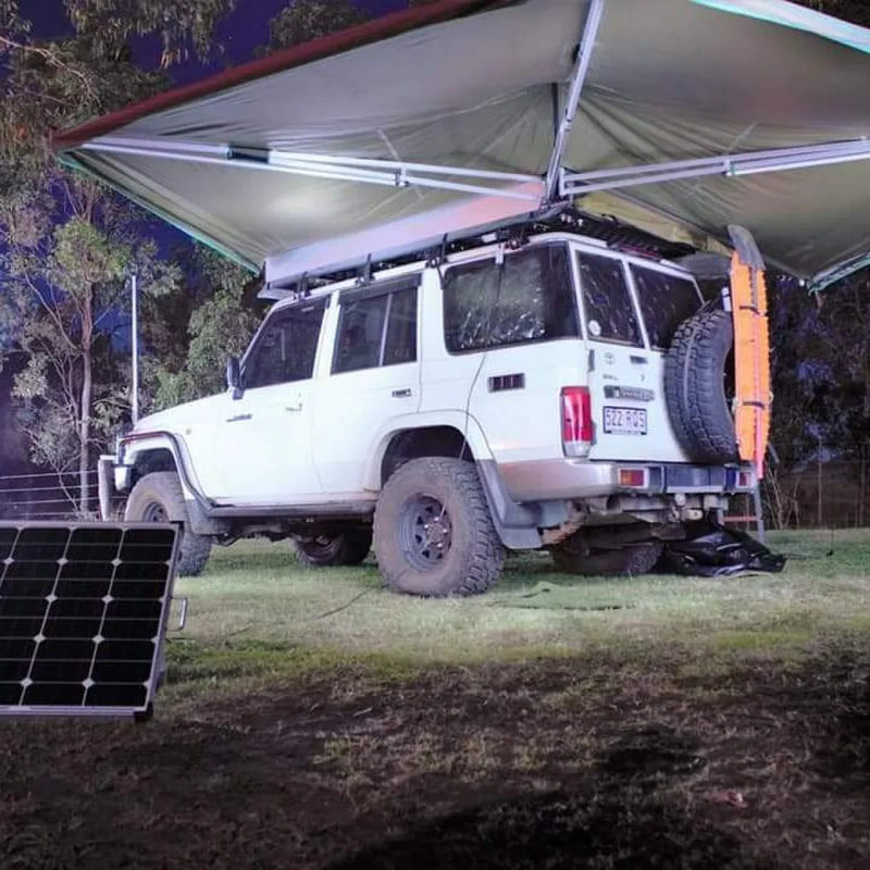 White off-road vehicle with second wing awning and solar panel on grass outdoors