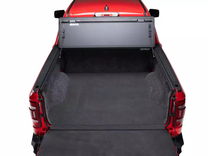 BAKFlip MX4 folded up against the cab of a red RAM 1500, showing the open tub from behind