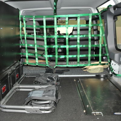 Cargo barrier net with green straps securing items in a vehicle’s rear compartment