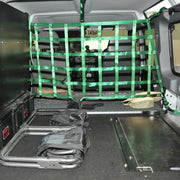 Cargo barrier net with green straps securing items in a vehicle’s rear compartment