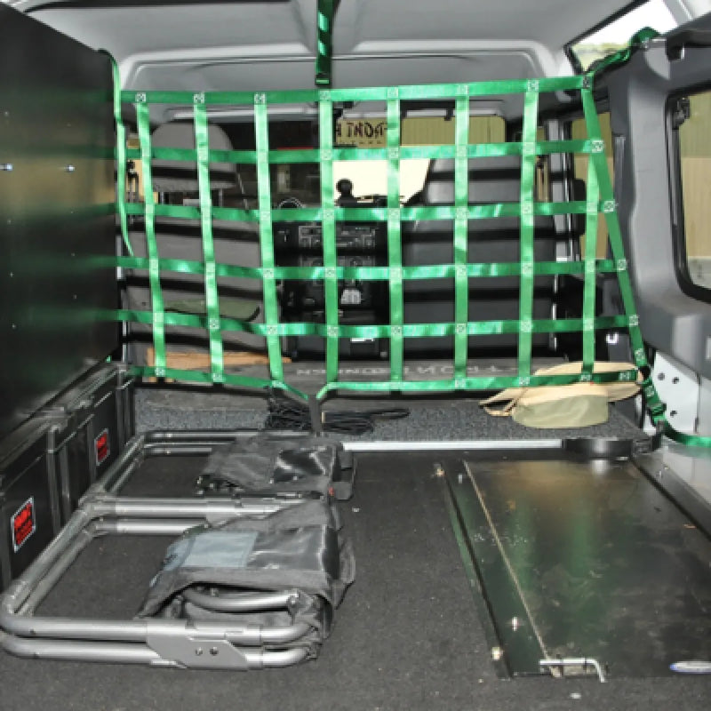 Cargo barrier net with green straps securing items in a vehicle’s rear compartment