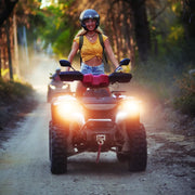 All-terrain vehicle with headlights on riding a dirt path, featuring quad bike electric capabilities