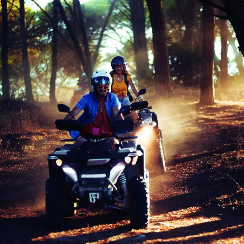 All-terrain vehicle carrying two riders on forest trail, highlighting synthetic rope and 4500lb ATV trailer winch