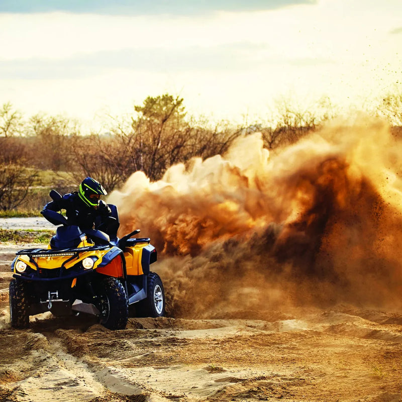 Yellow and black ATV kicking up dust while using Carbon 4500lb ATV Trailer Winch with synthetic rope