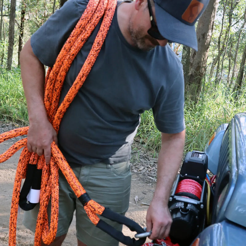 Bright orange Carbon Offroad kinetic recovery rope draped over a person’s shoulder