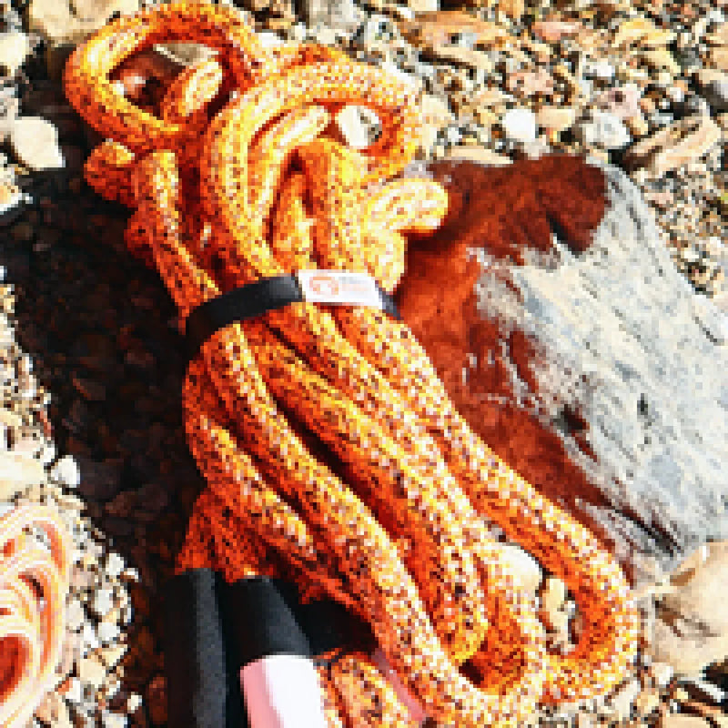 Coiled orange Carbon Offroad kinetic recovery rope on rocky ground for offroad recovery