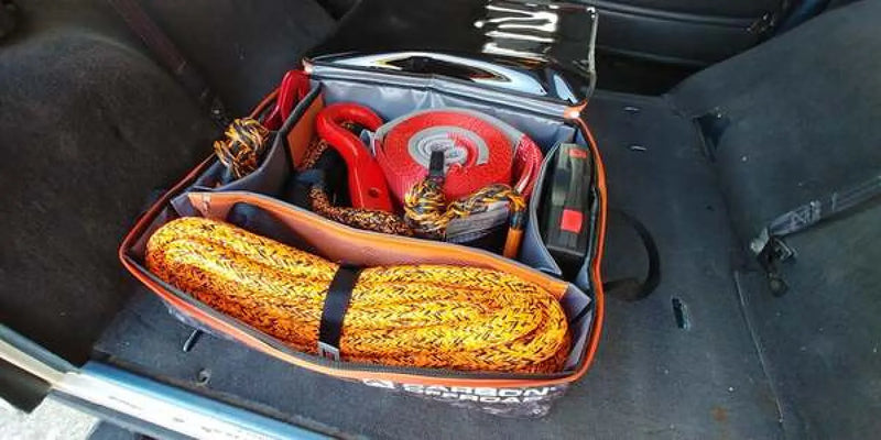 Coiled yellow rope or tow strap in red gear cube storage bag with emergency gear