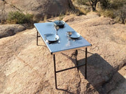 Eezi-Awn K9 Large Stainless Steel Camping Table with plates and glasses outdoors