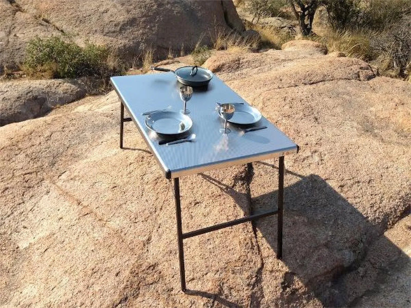 Eezi-Awn K9 Large Stainless Steel Camping Table with plates and glasses outdoors