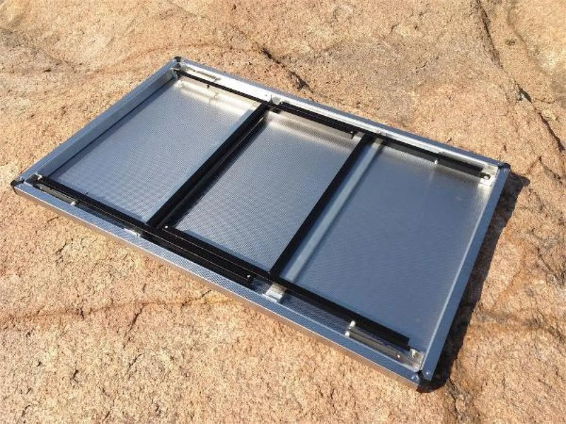 Folding solar panel with three sections on sandy ground for Eezi-Awn K9 Large Stainless Steel Camping Table
