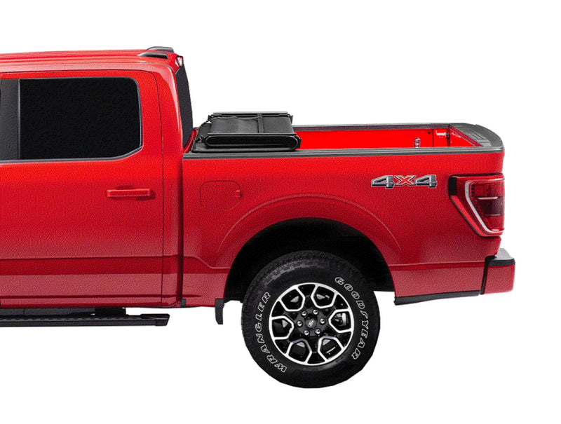 Red pickup truck with 4x4 badge and alloy wheels showcasing Extang Trifecta E-Series soft folding truck bed cover