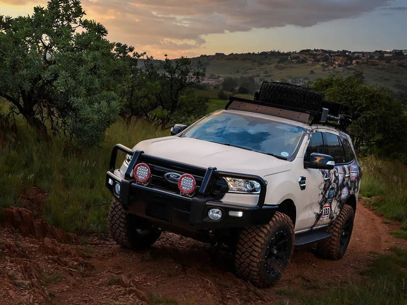 Rugged white off-road vehicle with Front Runner Ford Everest Slimline II roof rack kit on dirt path