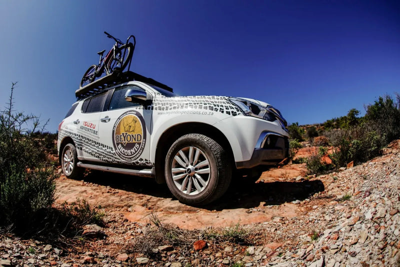 SUV with sponsor logo roof rack kit carrying bicycle on Front Runner Isuzu MU-X
