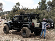 Black Jeep Wrangler with oversized tires and roof rack kit for off-road adventures