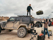 Rugged off-road vehicle with person on roof showcasing Front Runner Jeep Wrangler JK roof rack kit