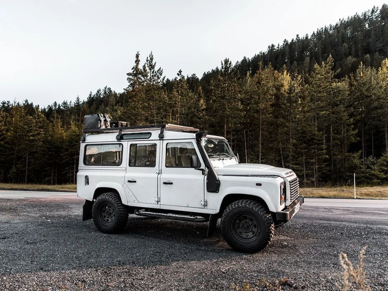 White Land Rover Defender with Front Runner LR Defender 110 Slimline II roof rack kit on road