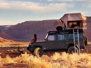 Off-road vehicle with rooftop tent using Front Runner LR Defender 110 Slimline II roof rack kit in desert landscape