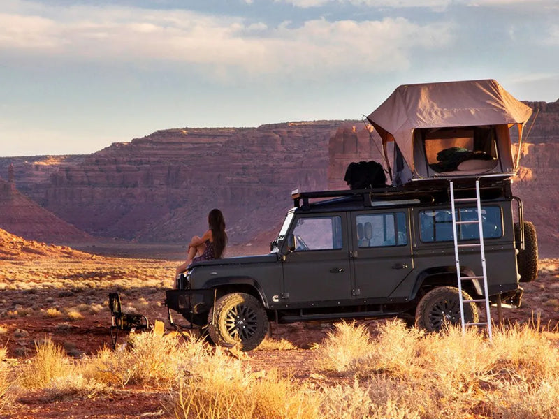 Off-road vehicle with rooftop tent using Front Runner LR Defender 110 Slimline II roof rack kit in desert landscape