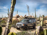 Off-road SUV with Front Runner LR Discovery LR3 LR4 Slimline II roof rack kit among desert cacti