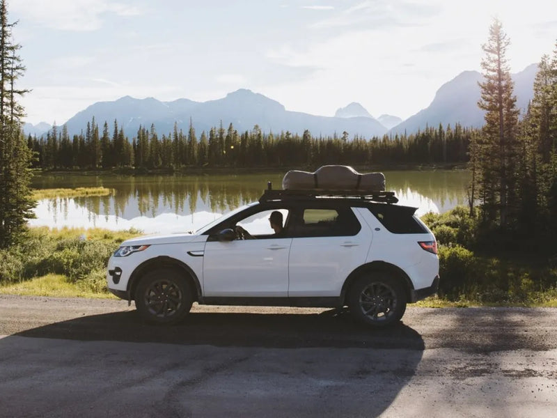 White SUV with Front Runner LR Discovery Slimline II Tray Roof Rack Kit by scenic lake