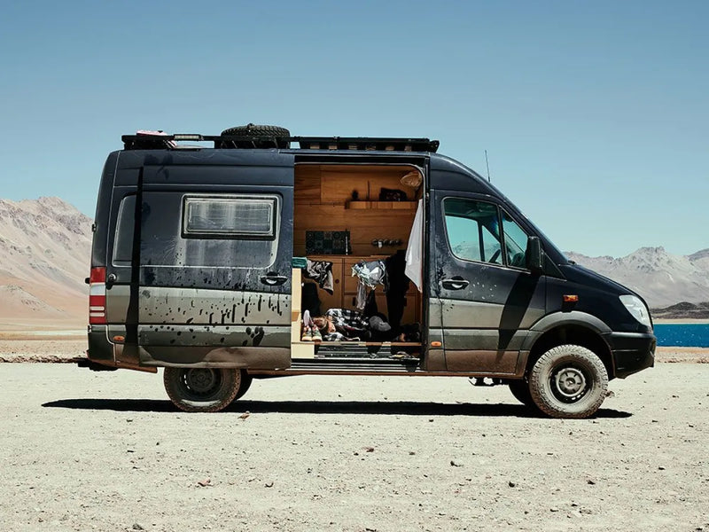 Converted Mercedes Benz Sprinter camper van with open side door showcasing cozy interior and Slimline II Tray