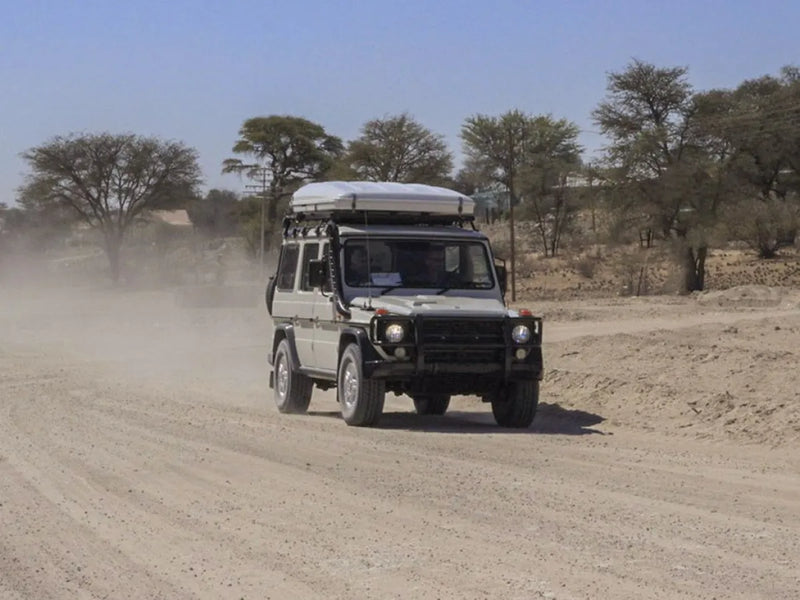 Off-road vehicle with roof rack kit driving on dusty dirt road for Mercedes Gelandewagen G Class