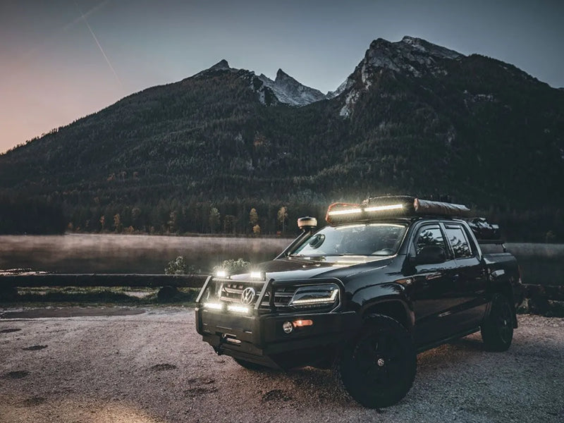 Rugged off-road vehicle with LED light bar and roof lights near mountains