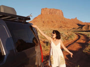 Woman in a white dress beside vehicle on desert road with Front Runner Premium Water Tank Hose Kit