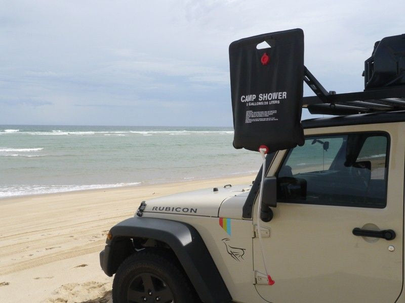 Jeep Wrangler Rubicon on beach with Front Runner Roof Rack Shower Arm Mount and portable shower