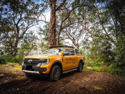 Yellow Ford Ranger pickup truck with Front Runner Slimline II Roof Rack Kit on a dirt path