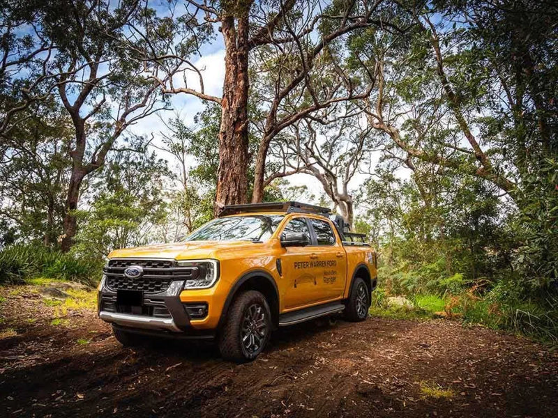 Yellow Ford Ranger pickup truck with Front Runner Slimline II Roof Rack Kit on a dirt path