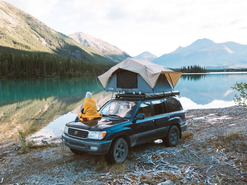 SUV with rooftop tent on Front Runner Toyota Land Cruiser 100 Slimline II roof rack kit by scenic lake