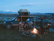 SUV with rooftop tent on Front Runner Land Cruiser rack kit in camping setting