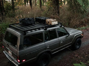 Gray Toyota Land Cruiser with Front Runner roof rack kit loaded with gear in forest