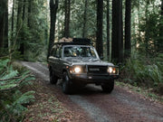 Toyota Land Cruiser with Front Runner roof rack kit driving on forest trail