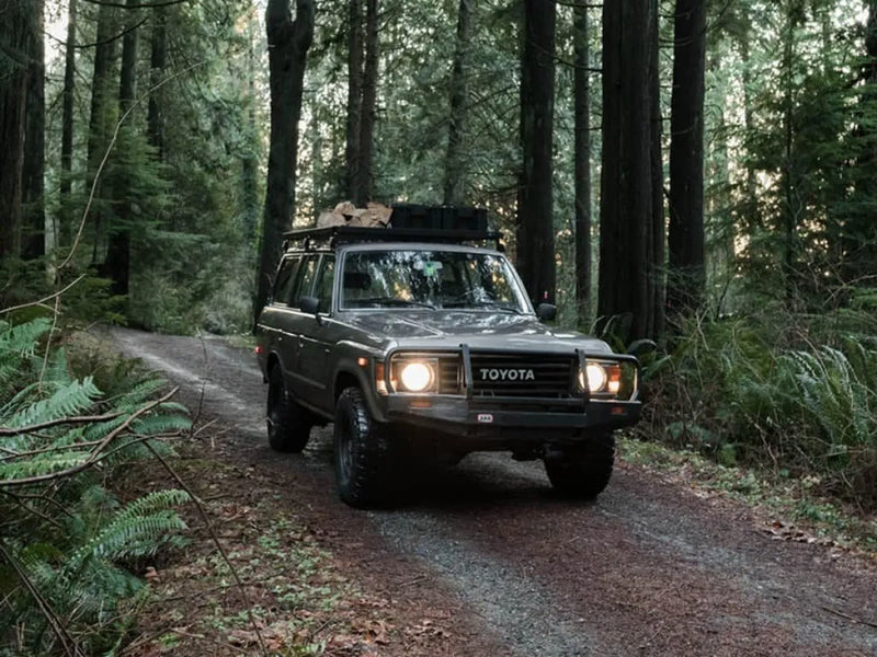 Toyota Land Cruiser with Front Runner roof rack kit driving on forest trail