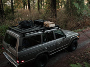 Off-road SUV with Front Runner Toyota Land Cruiser 60 Slimline II roof rack kit on forest trail