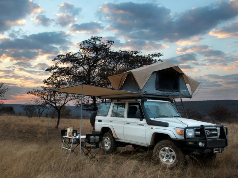 Off-road vehicle with rooftop tent showcasing Front Runner Toyota Land Cruiser 76 Slimline II roof rack kit in grassy field