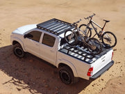 White pickup truck with bicycles on roof rack and load bed showcasing Front Runner Ute Slimline II Load Bed Rack Kit