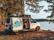 Camper van with open side door by lake, showcasing rooftop rack kit on T5/T6 Transporter