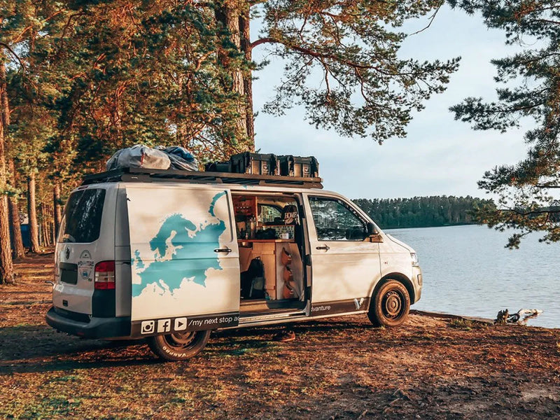 Camper van with open side door by lake, showcasing rooftop rack kit on T5/T6 Transporter