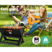 Portable charcoal BBQ grill with food cooking on the Grillz Notebook Portable Charcoal BBQ