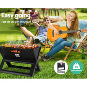 Portable charcoal BBQ grill with food cooking on the Grillz Notebook Portable Charcoal BBQ