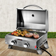 Portable stainless steel gas bbq with open lid showing grilled meats and vegetables