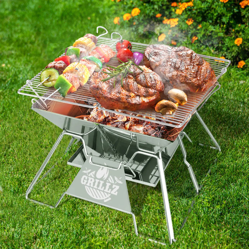 Portable barbecue grill with assorted meats and vegetables on compact 2-in-1 camping fire pit