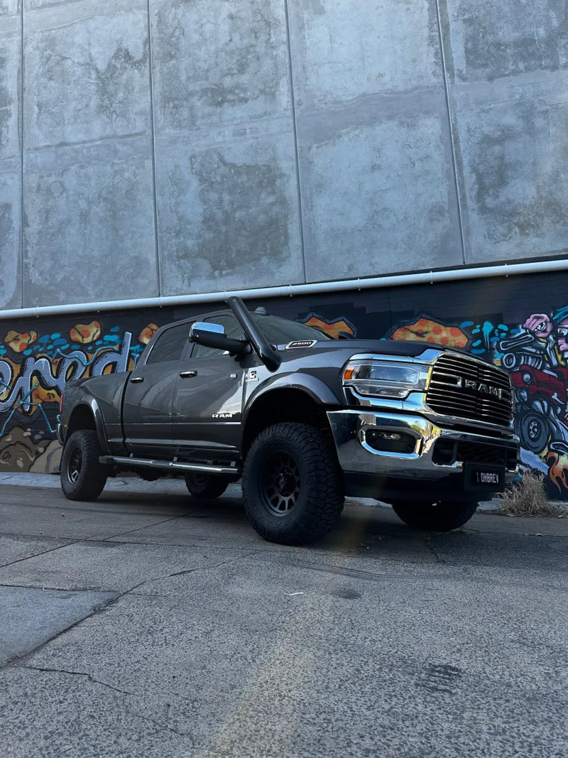 Black pickup truck with lifted suspension and stainless steel 5th gen snorkel kit in front of graffiti wall
