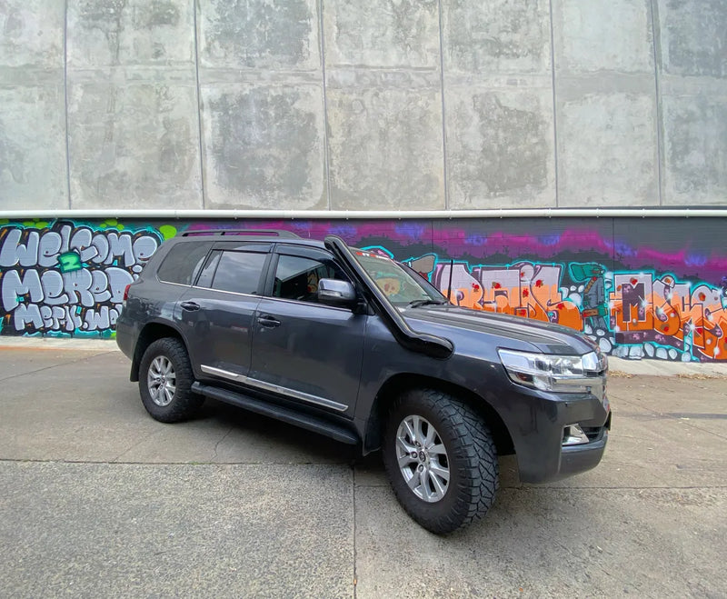 Gray SUV with stainless steel snorkel parked in front of graffiti wall