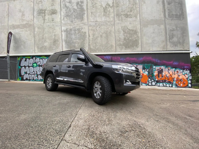 Black SUV with stainless steel snorkel parked in front of graffiti-covered wall